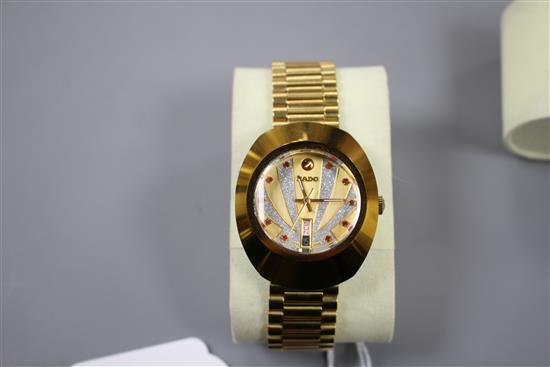 A gentlemans gilt steel Rado Diastar automatic wrist watch, with red stone set markers and textured dial, on Rado bracelet.
